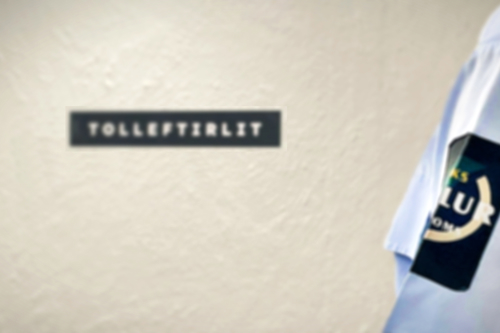 Tollari í tollaraskjúrtu. Í bakgrundini eitt skelti, har tolleftirlit stendur á.