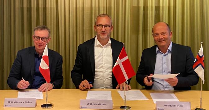 Umboð úr Grønlandi, Danmark og Føroyum sitandi við undirskrivingarborðið.